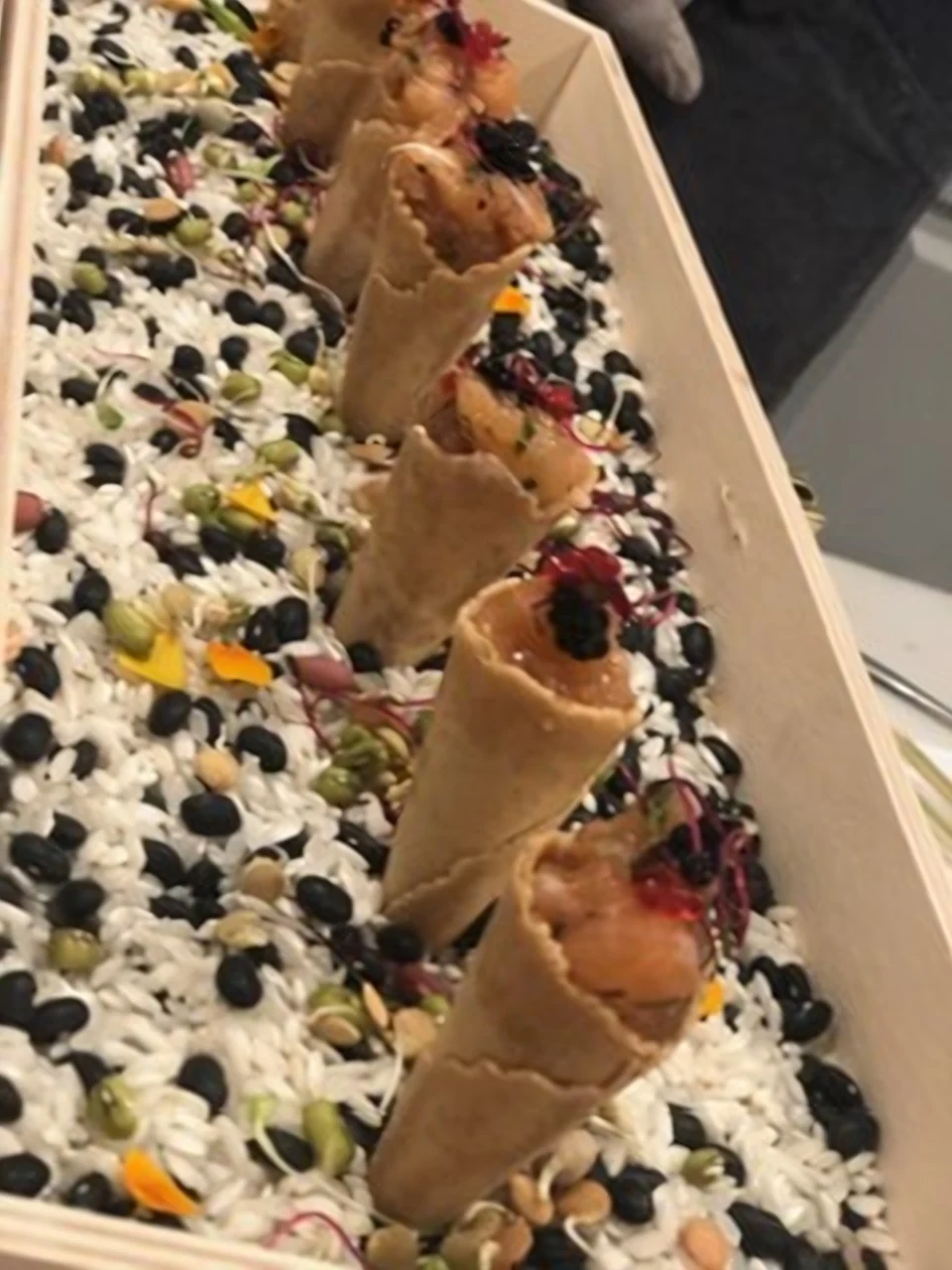 Spiced tuna tartare in crisp cones on a bed of black and white stones by Chef Paul Aceto