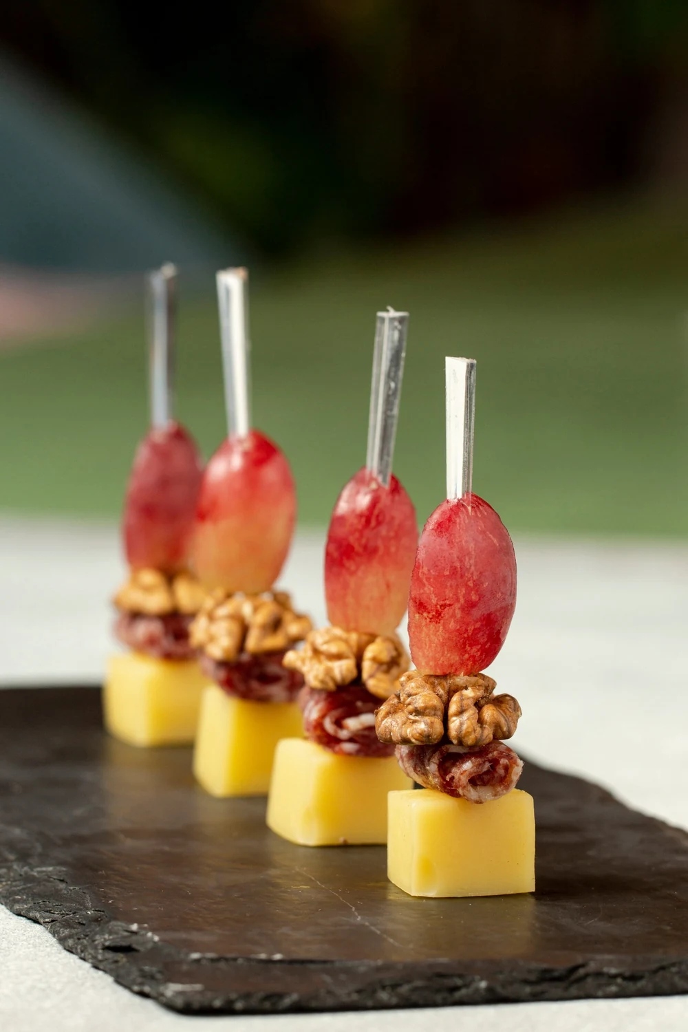 Cheese, salami, walnut and grape canapé skewers on slate — in-flight canapés for private jet catering in Miami